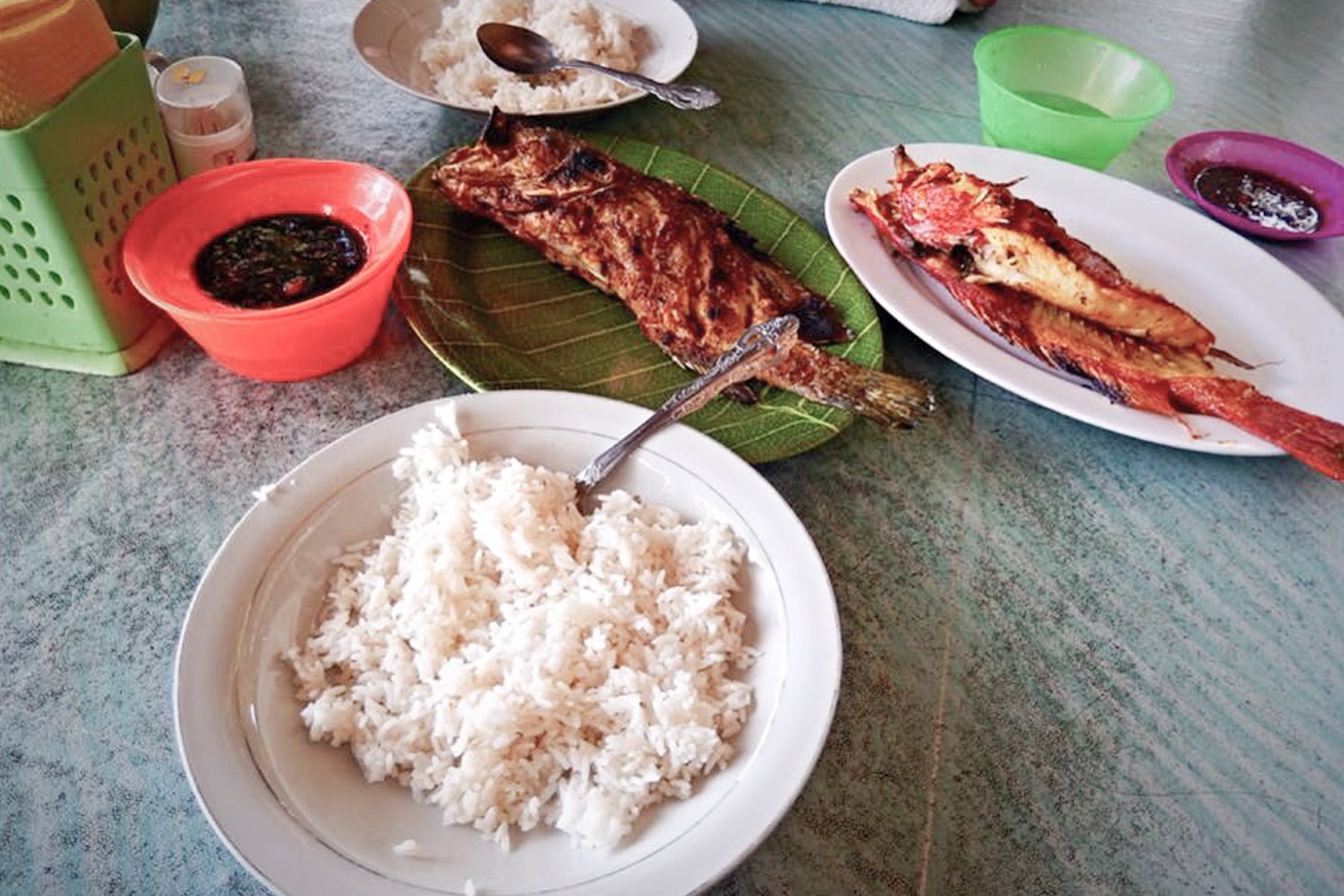 Image of a plate of rice and two plates of barbecue fish