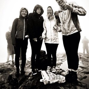 Image of four people standing in the rain on the top of a hill