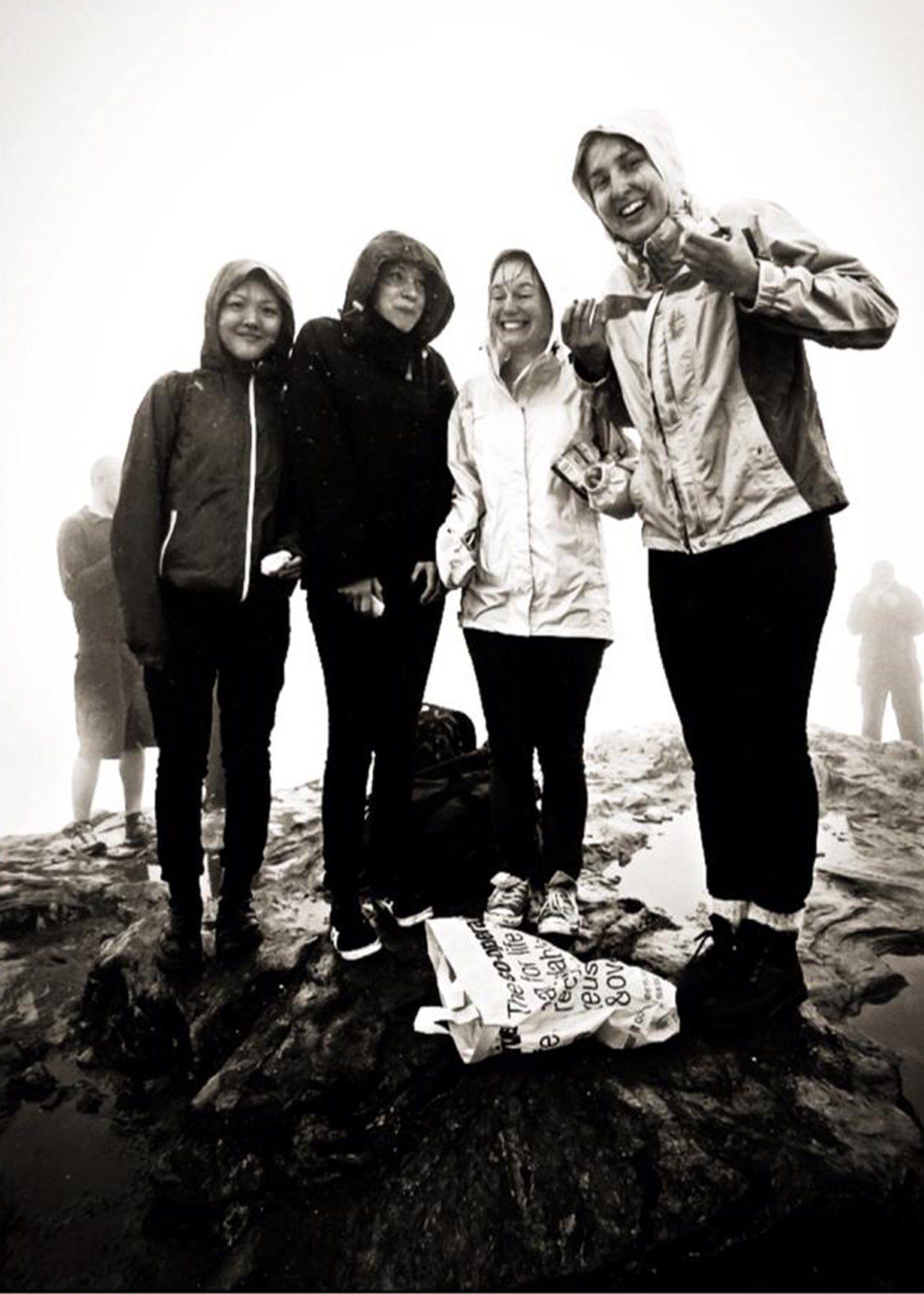 Image of four people standing in the rain on the top of a hill