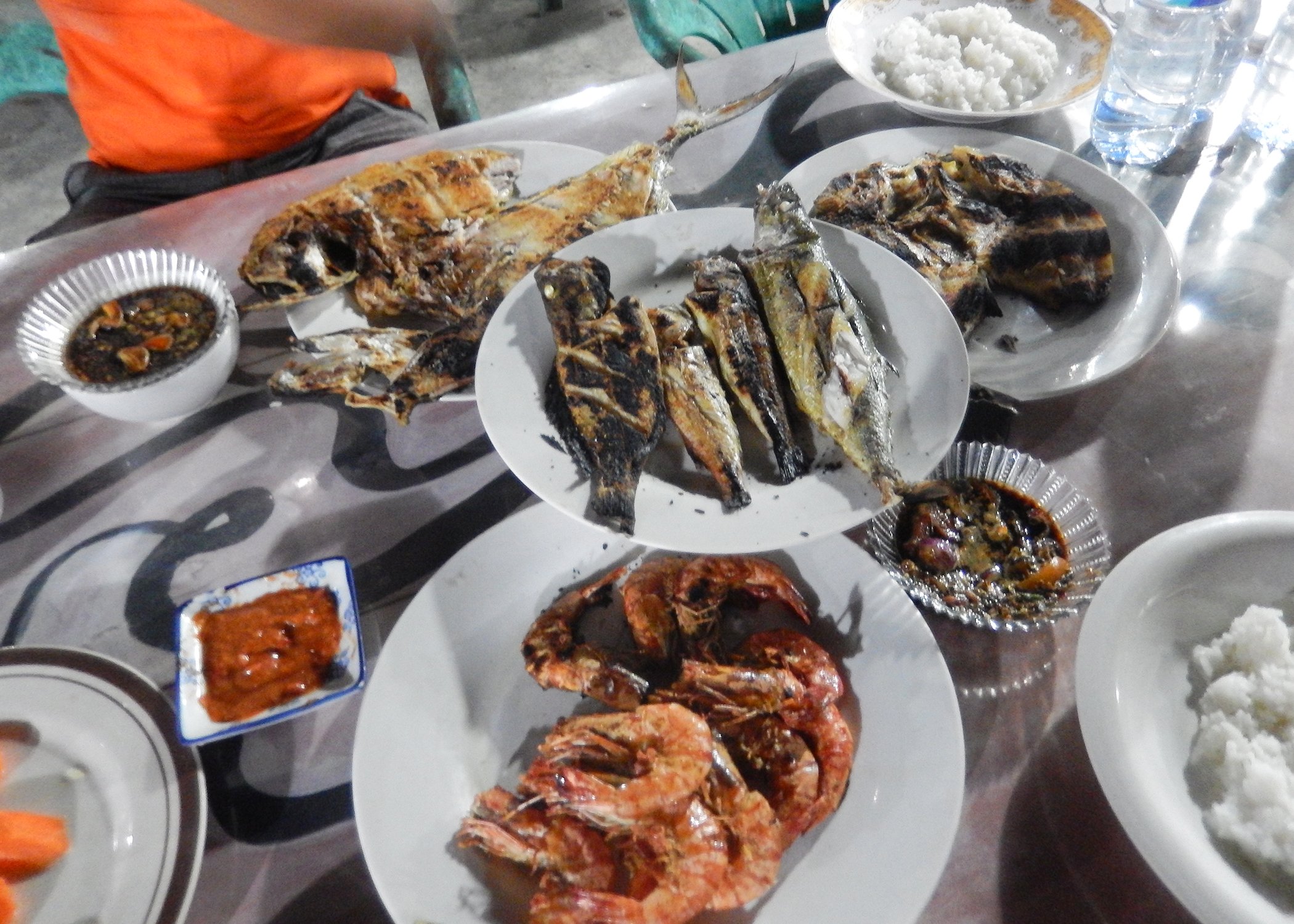 Image of plates of barbecue fish and prawns on a table