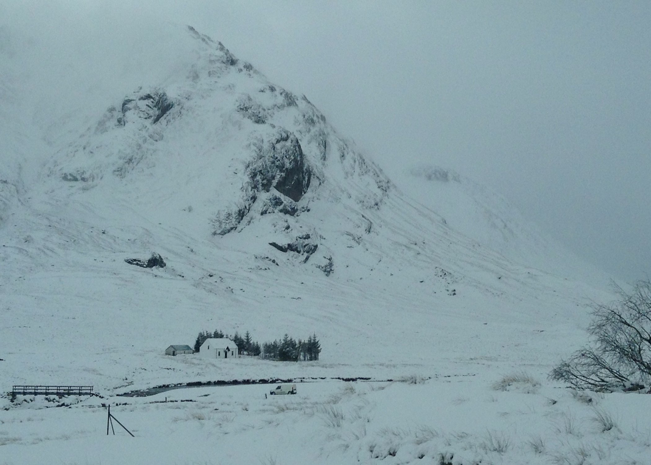 Image of a white snow covered hill and a white house in the distance