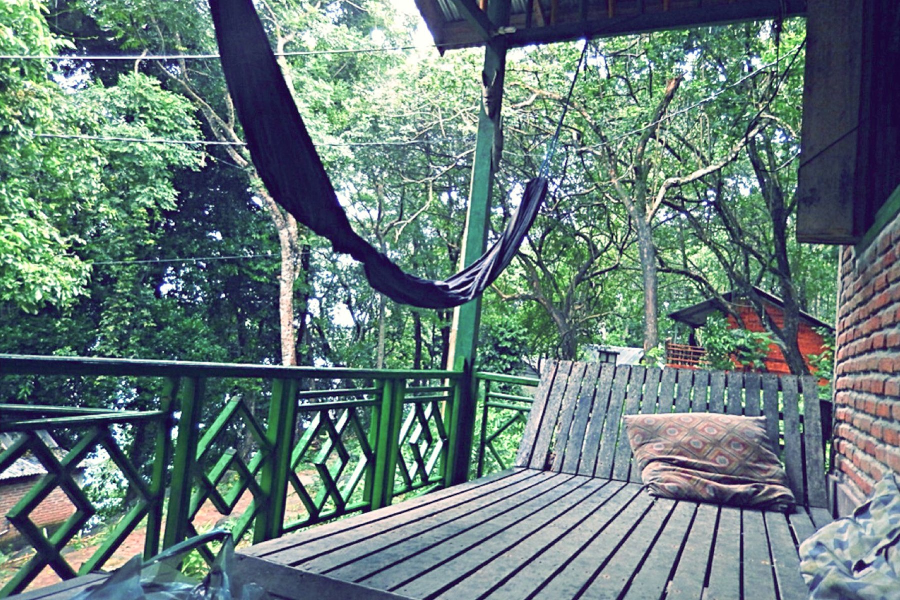 Image of a hammock and a bench next to a terrace in nature