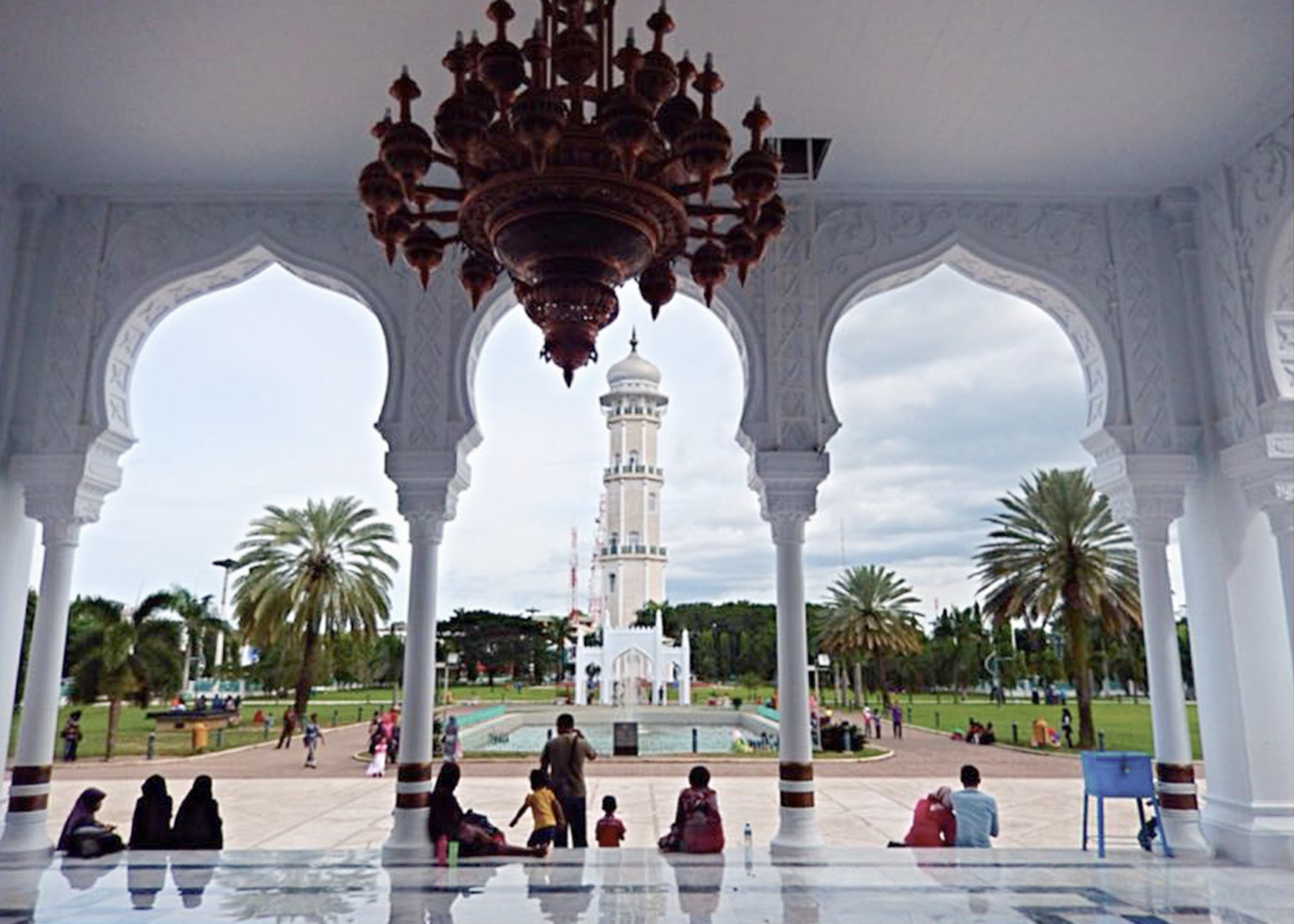 Image taken inside a mosque of people sitting at the edge of the entrance