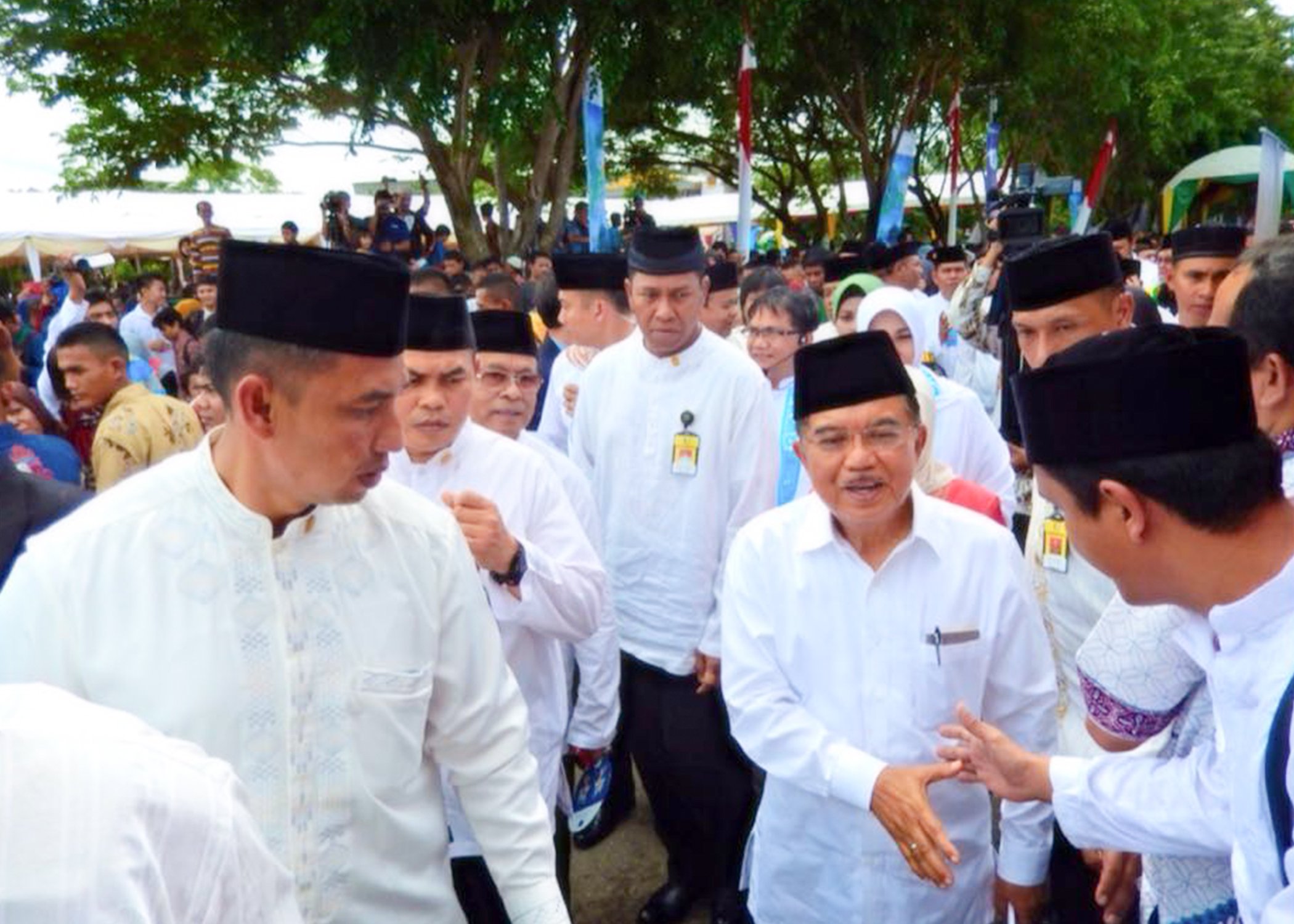 Image of the Vice President Jusuf Kalla walking and shaking hands with the public