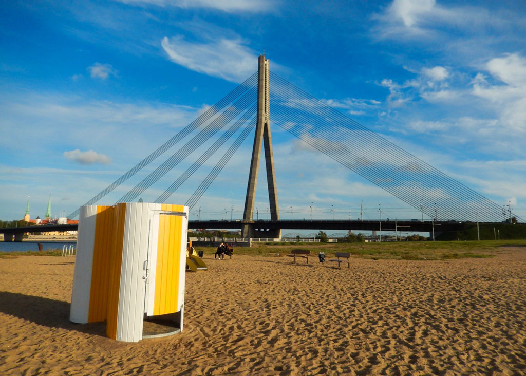 Image of a portable toilet with a large bridge in the background